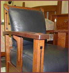 Detail of the dramatic design elements of the tapered arm which curves out in the center as it arches upward, the unusual wide single slat under the arm and the unique long corble attached to the slat under the arm.  True Ebony inlay in the front leg and back of chair. Please note the double pinned joinery where the top crest rail of the back is mortised into the top of the back leg and the large pinned through tenon extends above the top of the arm. 